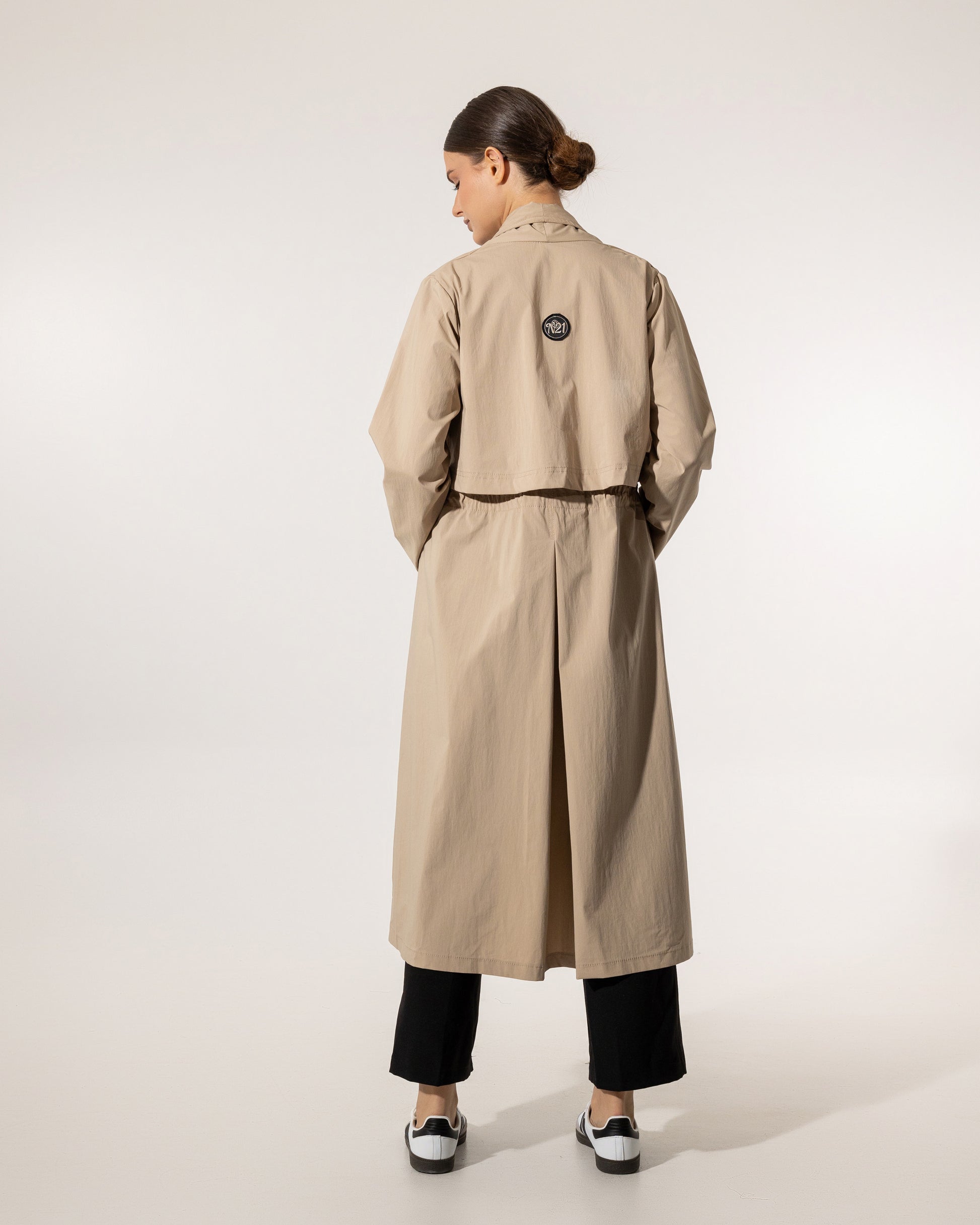 Person wearing a beige trench coat on a white background